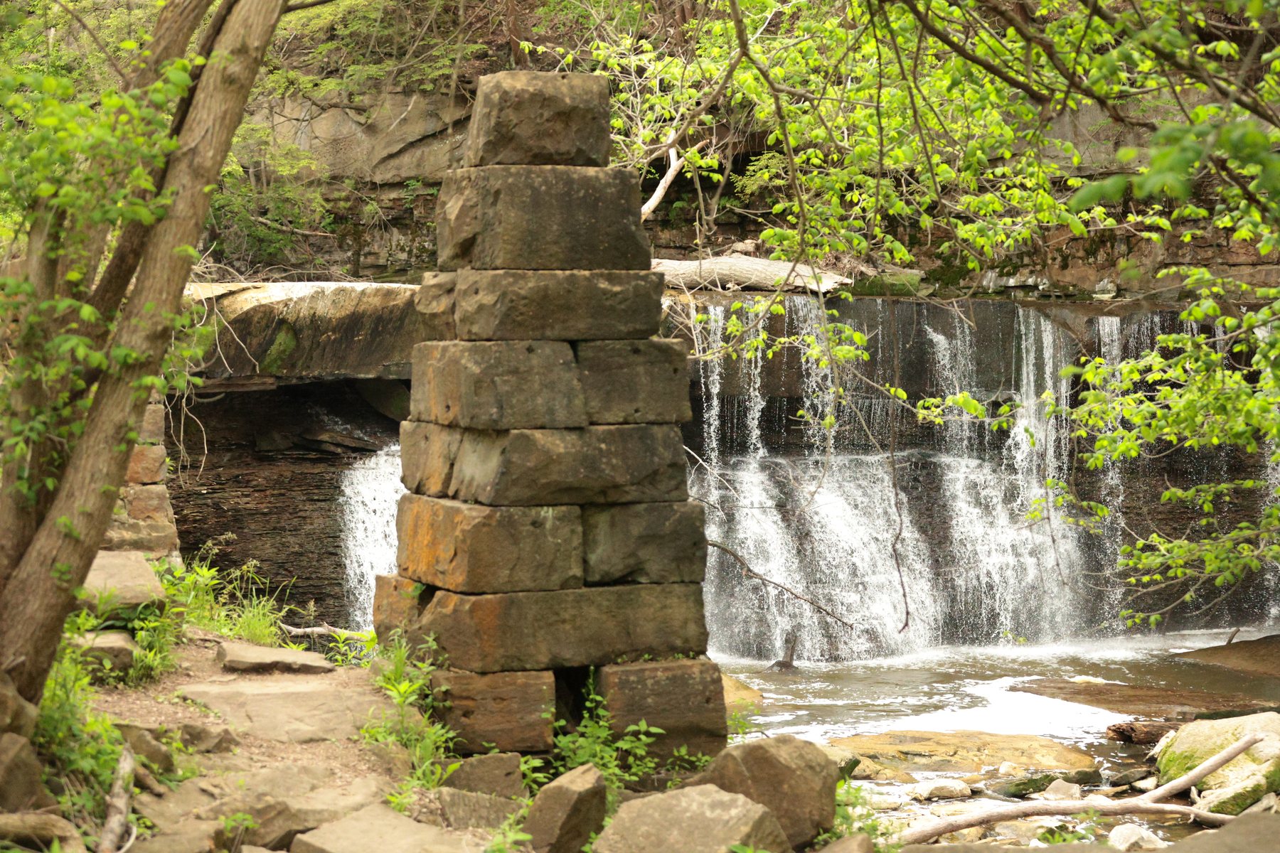 Waterfall framed by stone and trees.
